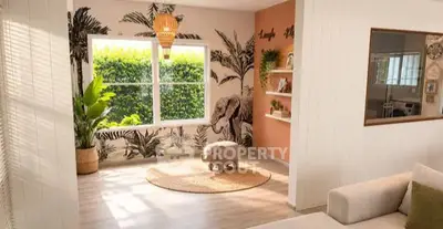 Charming living room with tropical decor and elephant theme, featuring large window and cozy seating area.