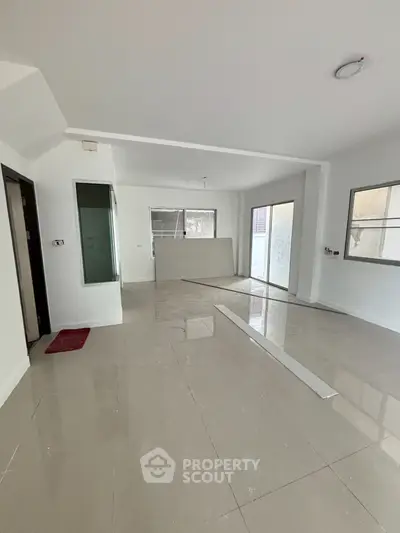 Spacious open-plan living area with large windows and modern tile flooring.