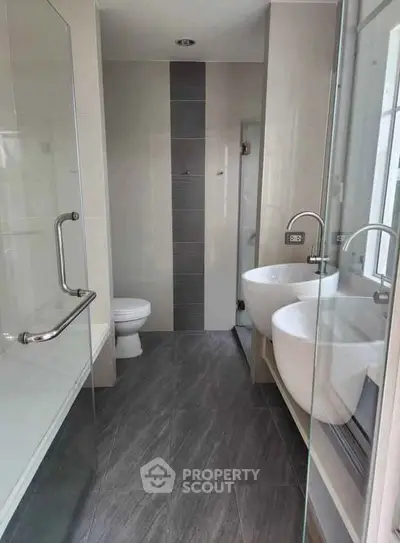 Modern bathroom with dual sinks and glass shower enclosure