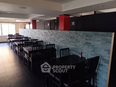 Spacious dining area with modern stone wall and ample natural light, perfect for gatherings.