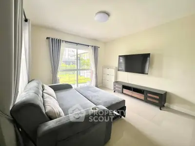 Spacious living room with modern sofa bed and large TV, bright natural light.