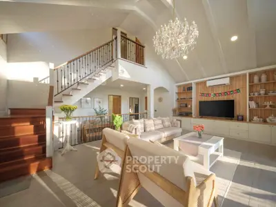 Spacious and elegant living room with high ceilings and chandelier, featuring modern decor and natural light.