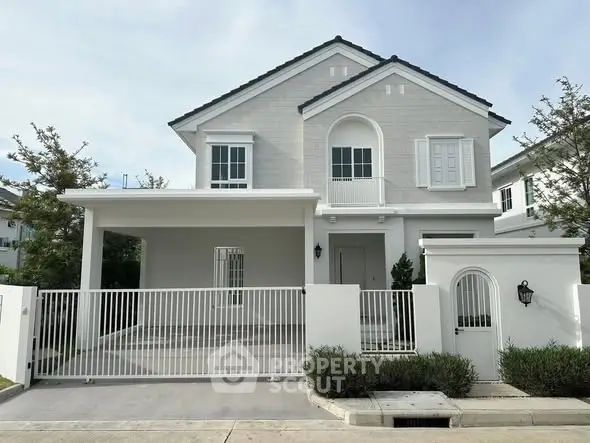 Charming two-story house with elegant facade and gated entrance in a serene neighborhood.