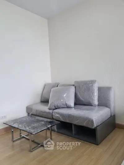 Modern living room with sleek gray sofa and stylish coffee table on wooden flooring.
