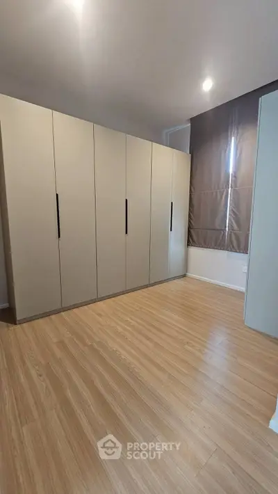 Spacious bedroom with sleek wardrobe and wooden flooring