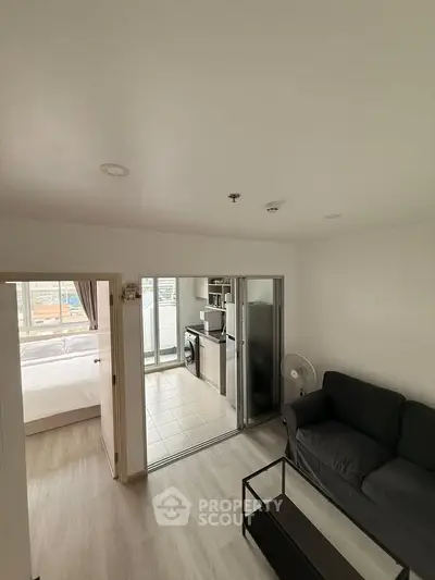 Modern apartment interior with open layout, featuring a cozy living room and a glimpse of the bedroom and kitchen.