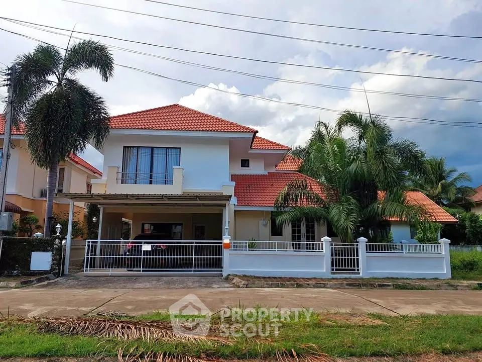 Charming two-story house with red-tiled roof and lush palm trees