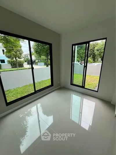 Bright room with large windows offering lush garden views, perfect for a serene living space.