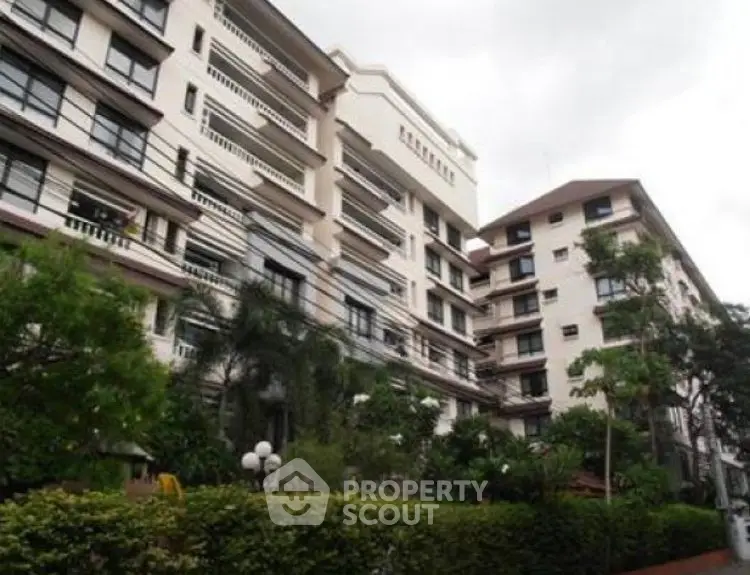 Elegant multi-story residential building with lush greenery and modern architecture.