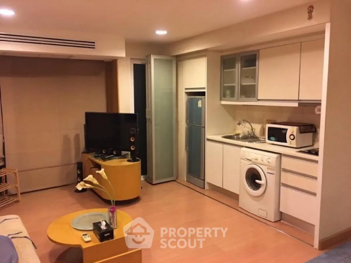 Modern studio apartment with compact kitchen and washing machine