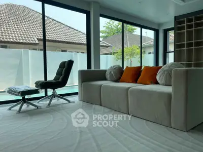 Modern living room with pool view, featuring stylish furniture and large windows for natural light.