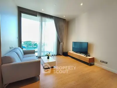 Modern living room with sleek furniture and large window offering natural light.