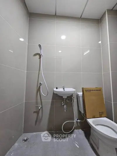 Modern bathroom with sleek tiles and compact fixtures, ideal for efficient space utilization.