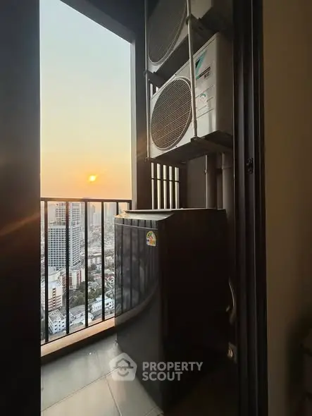High-rise balcony with city view and air conditioning units at sunset.
