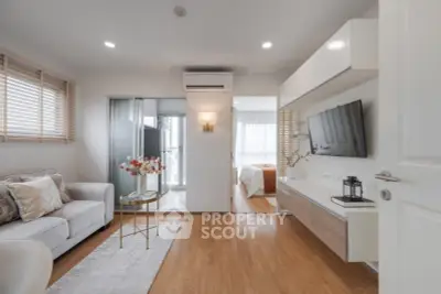 Modern living room with wooden flooring and stylish decor leading to a cozy bedroom.