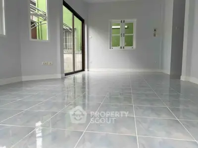 Spacious empty room with glossy tiled floor and large windows for natural light.