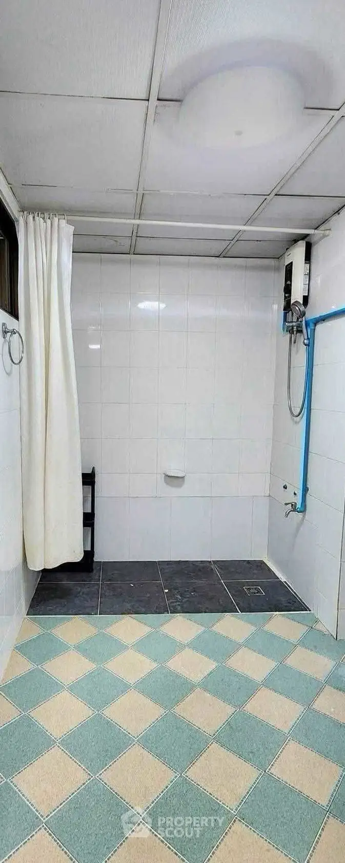 Spacious bathroom with tiled walls and floor, featuring a shower area and water heater.