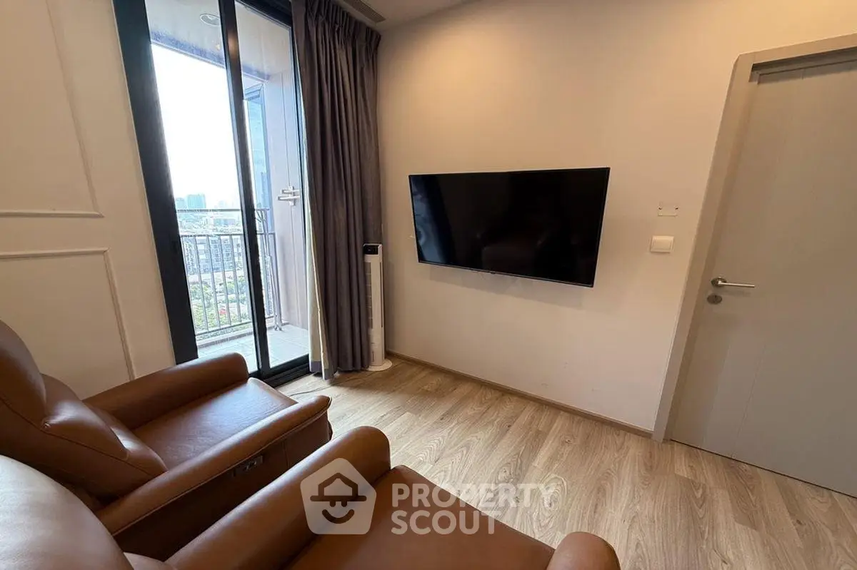 Modern living room with sleek TV and balcony view, featuring elegant leather seating and wooden flooring.
