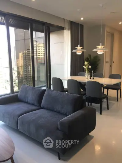 Modern living room with large windows and stylish dining area in a high-rise apartment.