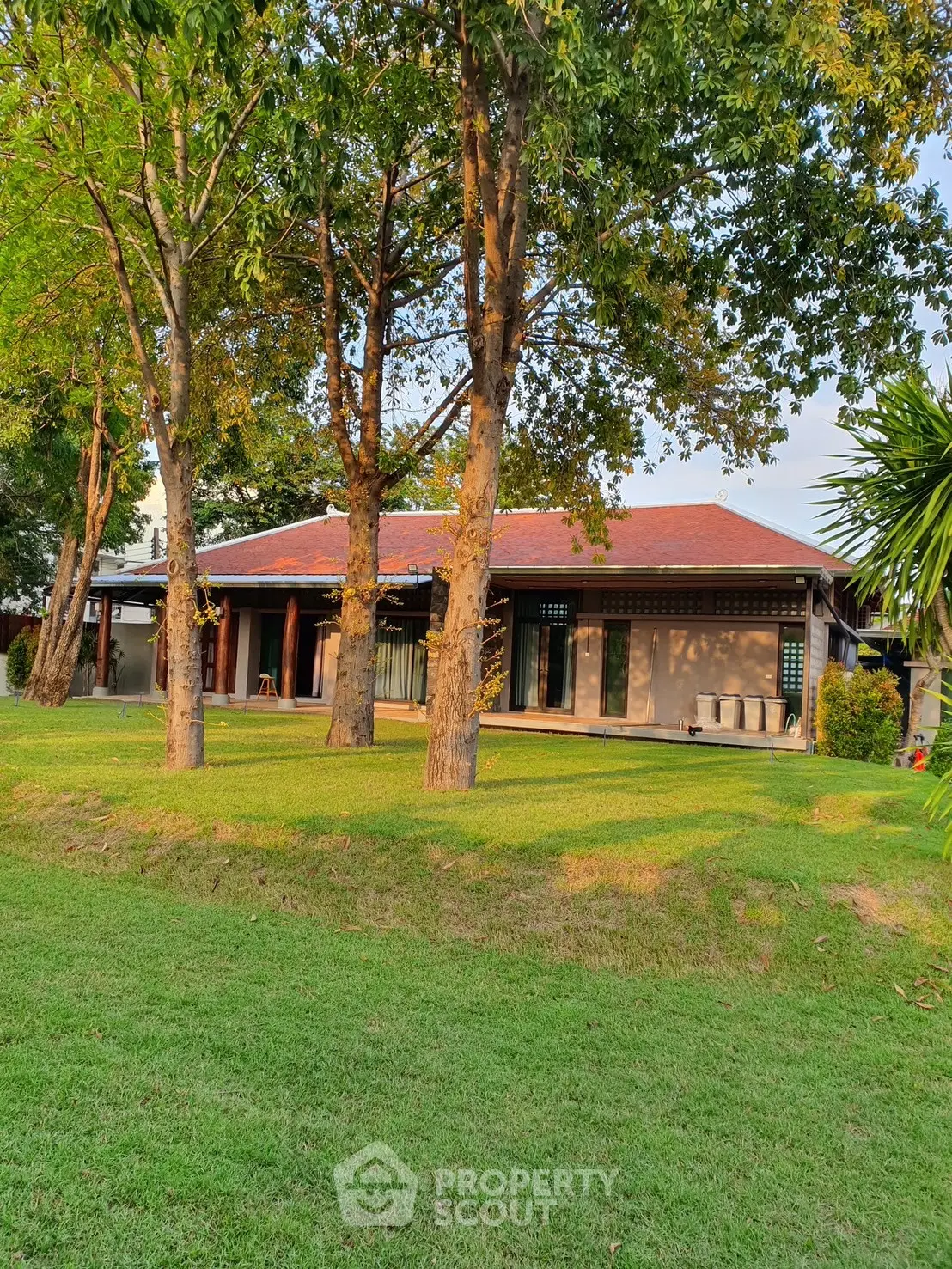 Charming single-story home with lush green lawn and mature trees, perfect for serene living.