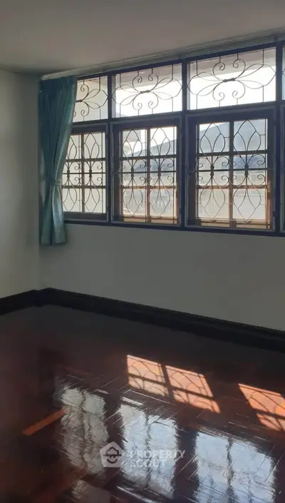 Spacious room with elegant windows and polished wooden floors, perfect for customization.