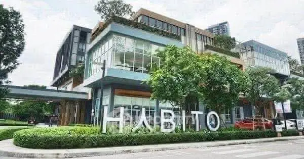 Modern commercial building with glass facade and lush greenery in urban setting.