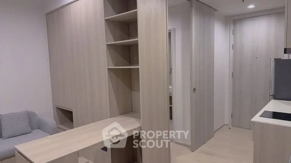 Modern apartment interior with sleek wooden cabinetry and cozy seating area.