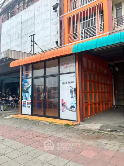 Vibrant commercial property with glass facade and orange accents, ideal for retail or office space.