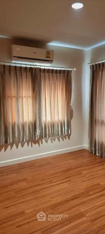 Spacious room with wooden flooring and air conditioning, perfect for a cozy living space.