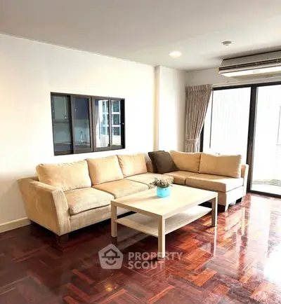 Spacious living room with elegant wooden flooring and cozy beige sofa