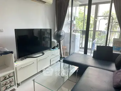 Modern living room with sleek furniture and balcony view, featuring a large TV and glass coffee table.
