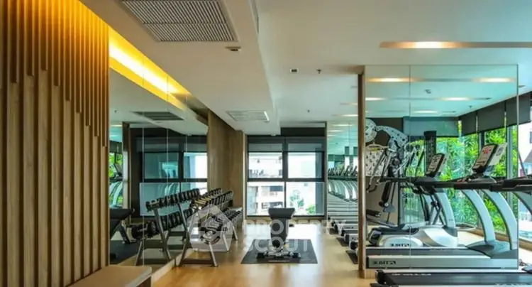 Modern gym with state-of-the-art equipment and mirrored walls in luxury apartment complex.