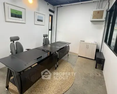 Modern office space with sleek black desks and ergonomic chairs, featuring minimalist decor and natural lighting.