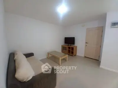 Cozy living room with sofa, TV, and coffee table in a minimalist style apartment.