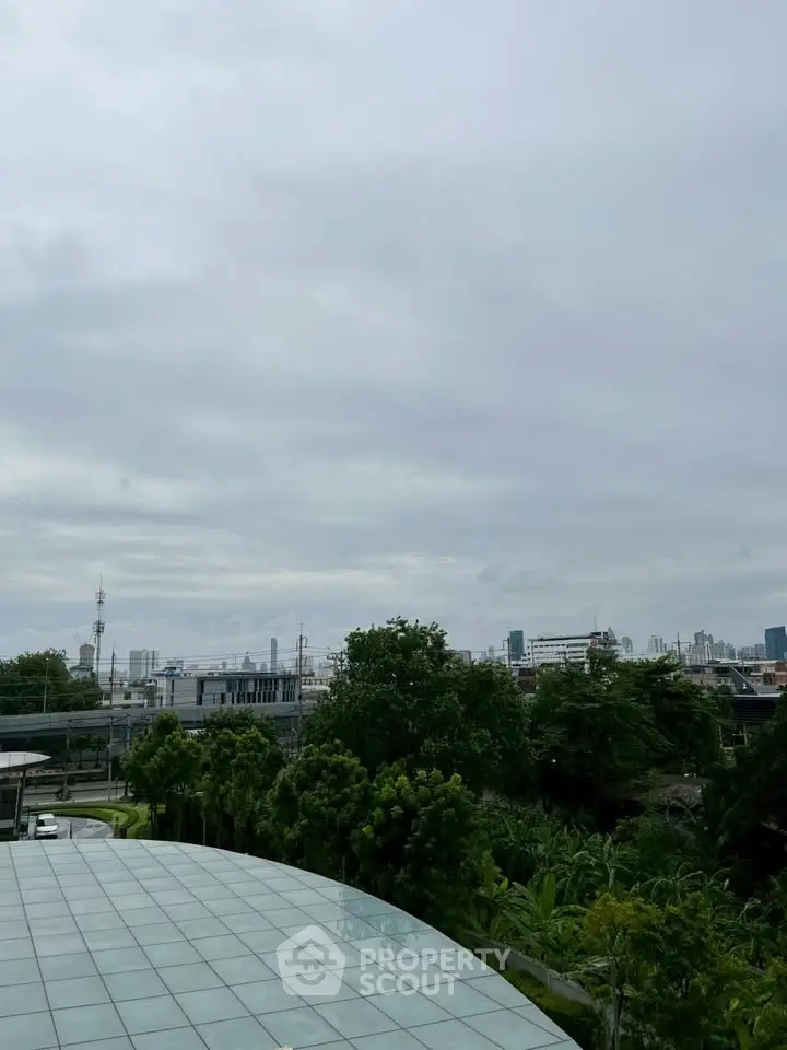 Stunning cityscape view from a modern rooftop with lush greenery and skyline in the background.
