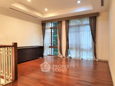 Spacious living room with elegant wooden flooring and large windows for natural light.