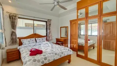Spacious bedroom with wooden furniture and large mirrored wardrobe