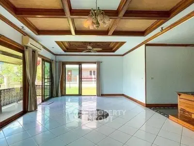 Spacious living room with elegant coffered ceiling and large windows opening to a garden view.