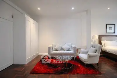 Elegant living room with modern furniture and vibrant red rug, perfect for stylish urban living.