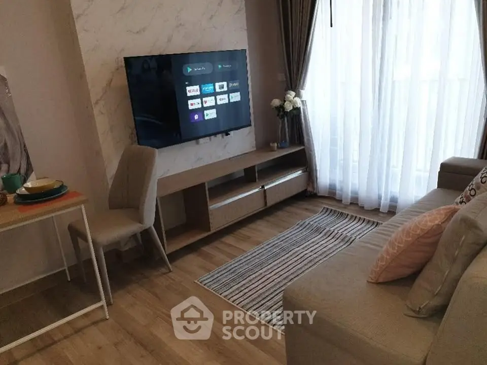 Modern living room with wall-mounted TV, cozy sofa, and elegant decor in a bright apartment.