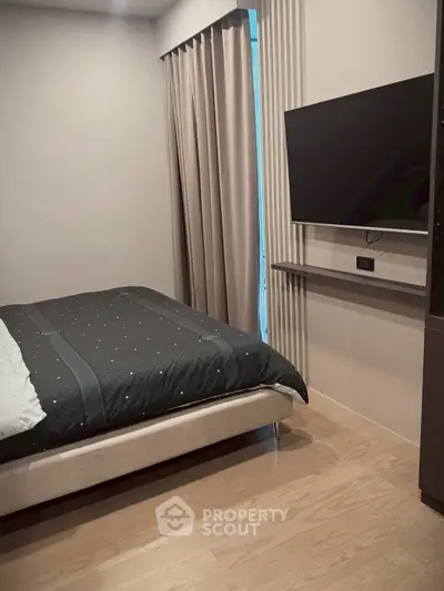 Modern bedroom with sleek TV setup and elegant curtains