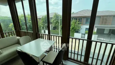 Spacious living room with large windows offering a serene view of modern houses and lush greenery.