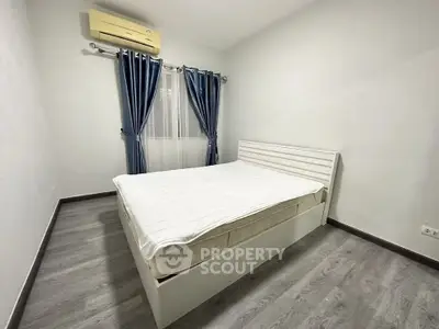 Spacious bedroom with modern decor and air conditioning, featuring elegant blue curtains and sleek flooring.