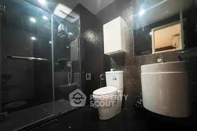 Modern bathroom with sleek black tiles and glass shower enclosure