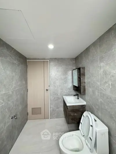 Modern bathroom with sleek design and neutral tones, featuring a toilet and vanity.