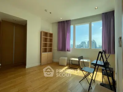 Spacious apartment room with wooden flooring and city view, featuring modern furniture and large windows.