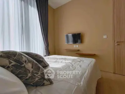 Cozy bedroom with modern decor and wall-mounted TV, featuring elegant curtains and neutral tones.