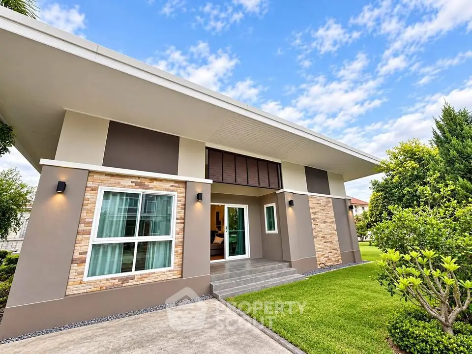 Modern single-story home with sleek design and lush green lawn under a clear blue sky.