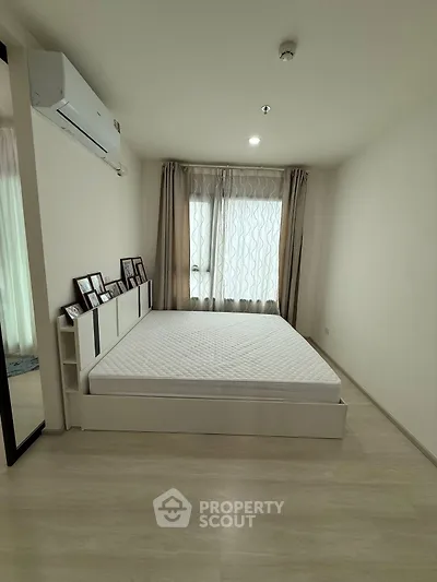 Spacious bedroom with modern decor and large window for natural light.