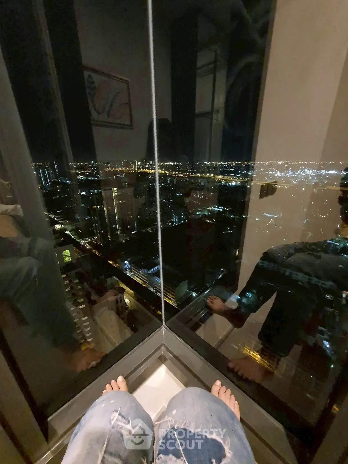 Stunning high-rise city view from a modern apartment corner window at night.